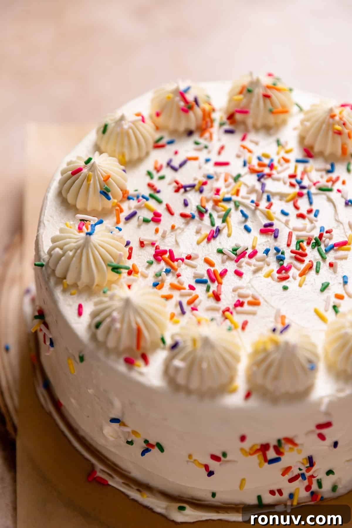 Homemade Funfetti Cake That Beats the Bakery 8 White sprinkle cake with dollops of buttercream on top.