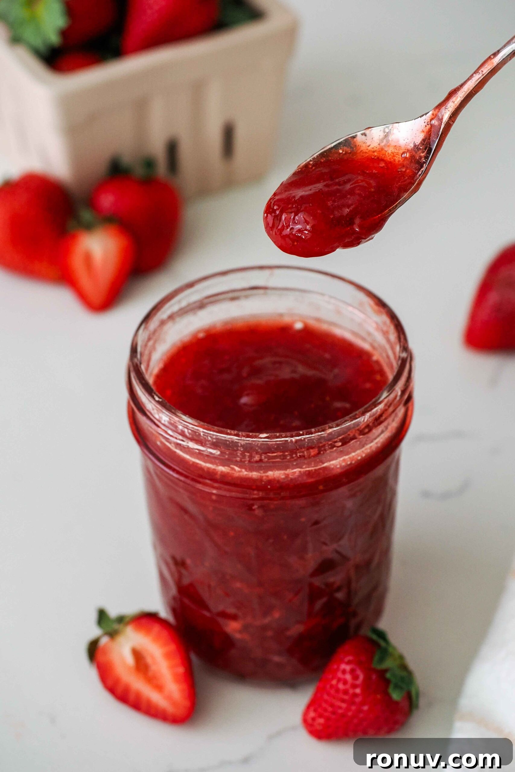 How to Make Small-Batch Strawberry Jam 2 A spoon with strawberry jam over an open jar of jam.