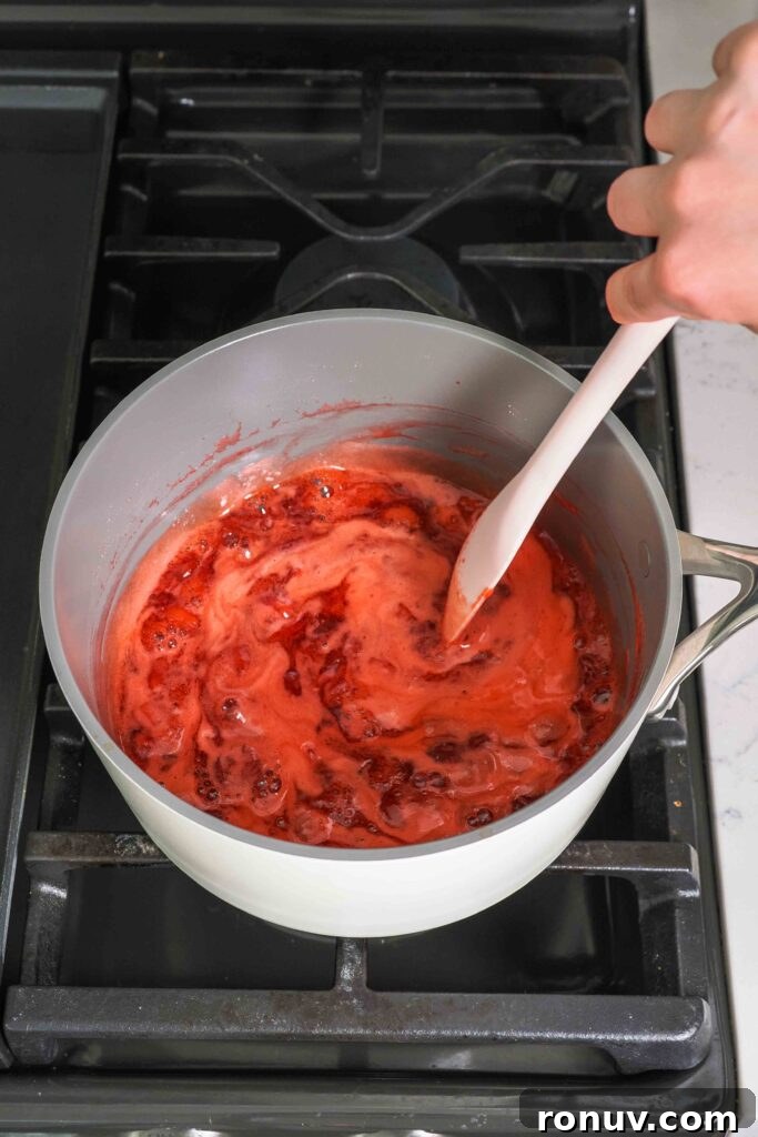 How to Make Small-Batch Strawberry Jam 7 A spatula stirs strawberry jam in a pot.
