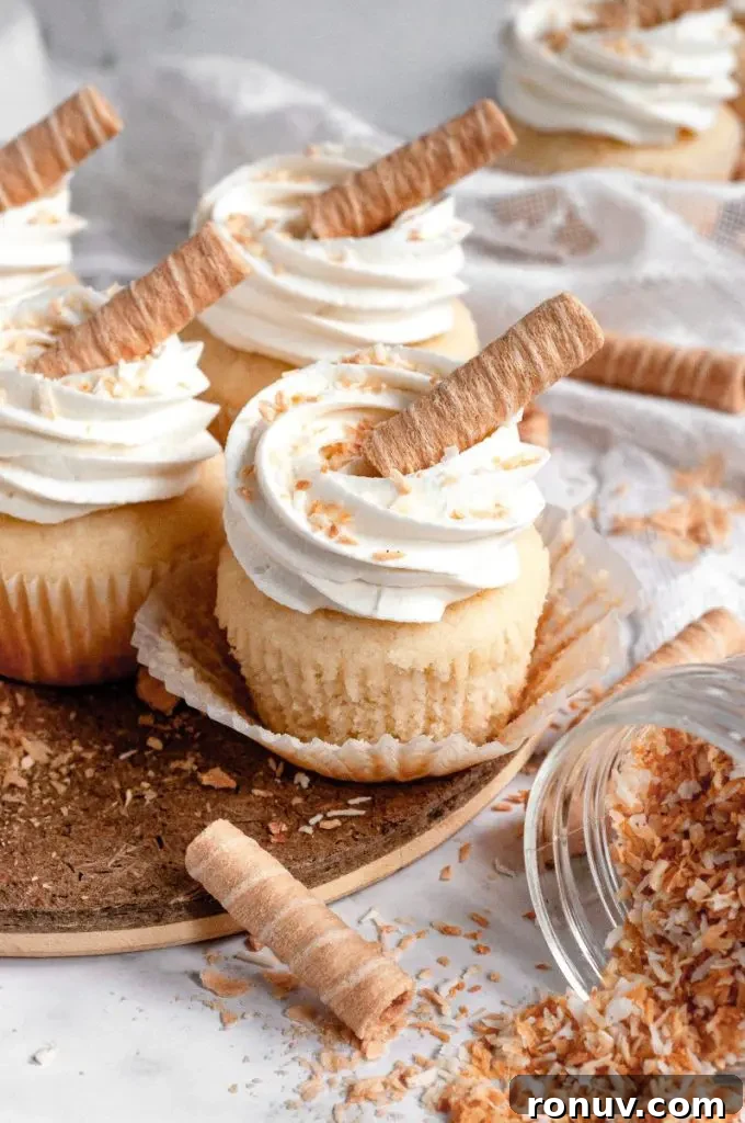 Gluten-Free Cupcakes: Moist, Bakery-Style Recipes 5 Light golden coconut cupcakes topped with white whipped cream cheese frosting with some toasted coconut sprinkled on top.