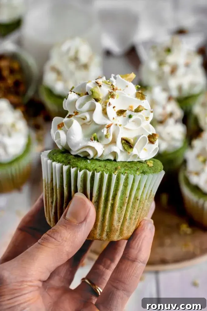 Gluten-Free Cupcakes: Moist, Bakery-Style Recipes 6 Bright green pistachio cupcakes topped with white cream cheese frosting and some sprinkled chopped pistachios.