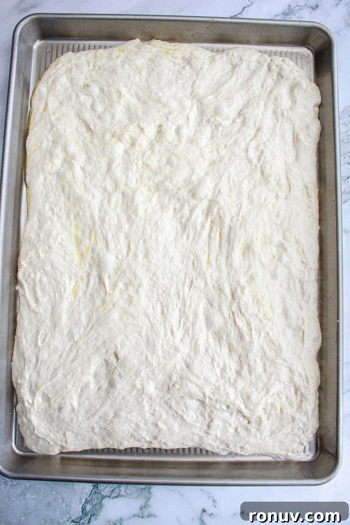 Tomato Focaccia: Classic Italian Bread 7 dough being pressed into a large rimmed baking sheet,