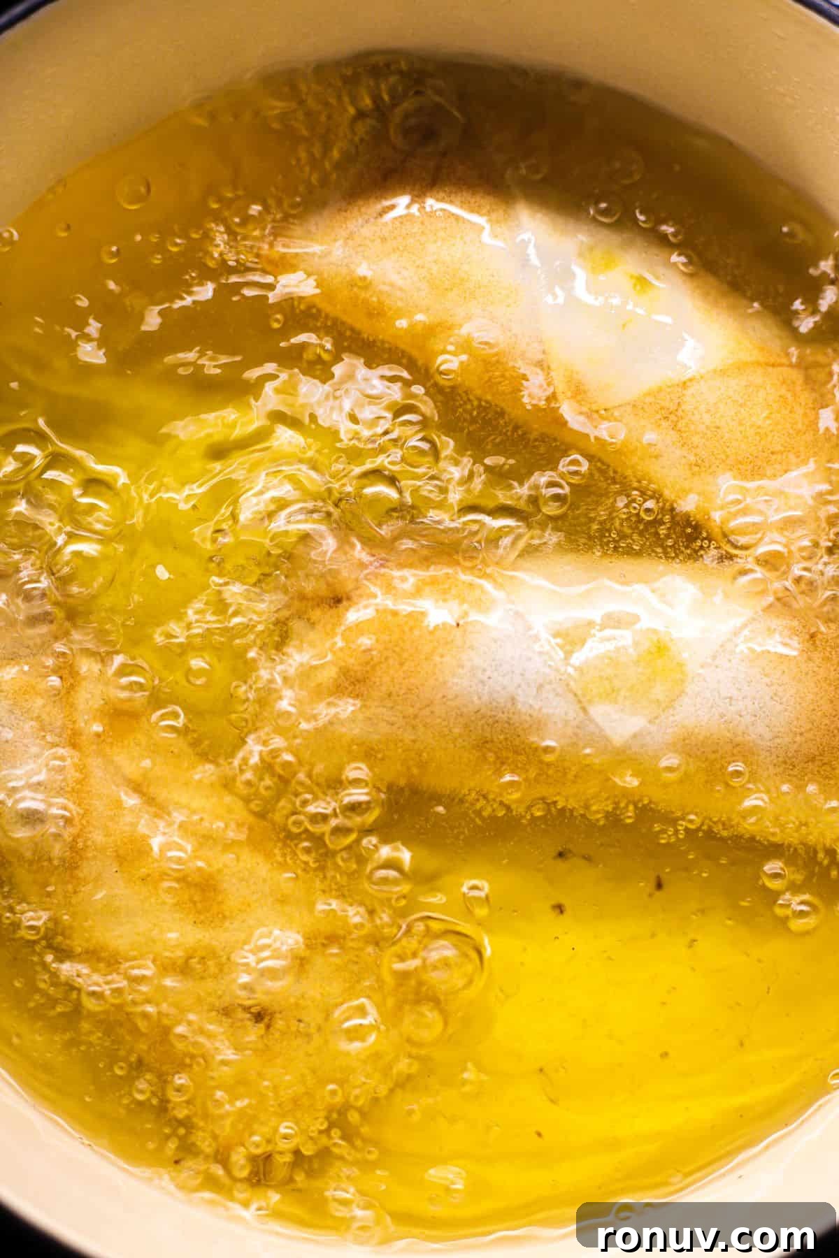Crispy Golden Vegetable Spring Rolls with Sweet Chili Sauce 7 Spring rolls being deep fried in a skillet.