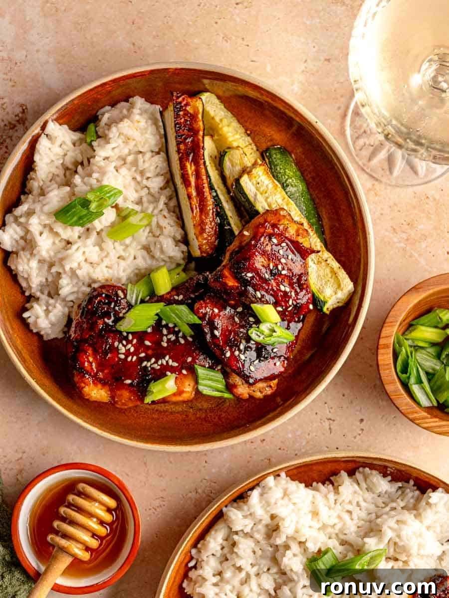 Sticky Honey Garlic Chicken Thighs for Quick Weeknight Dinner 8 Chicken rice and zucchini on a plate next to a glass of wine.