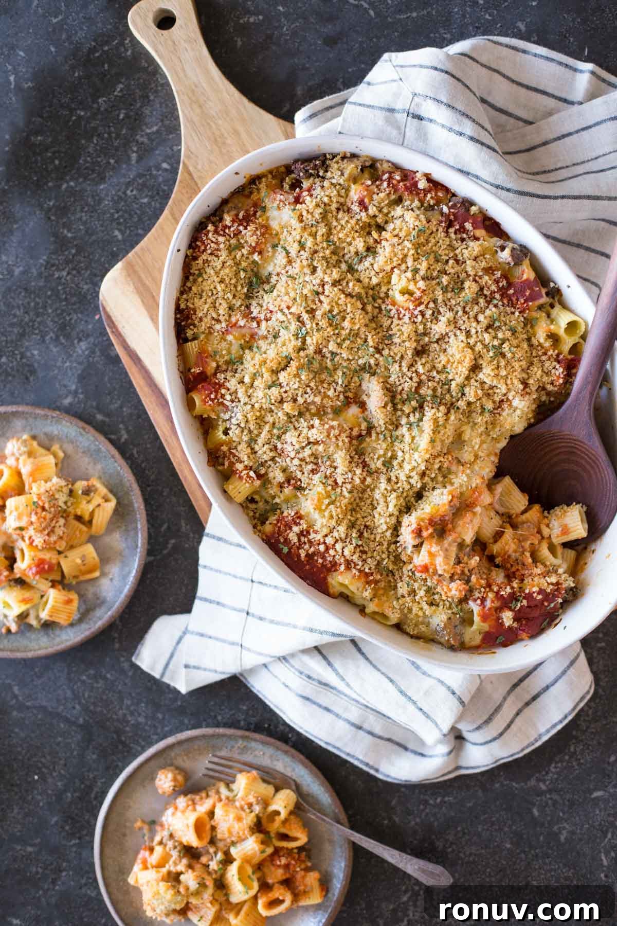Creamy Tomato Alfredo Pasta Bake with Melted Mozzarella 2 Cheesy Tomato Alfredo Pasta Bake in a baking dish with a serving spoon in it, with two plates of the Cheesy Tomato Alfredo Pasta Bake next to it.
