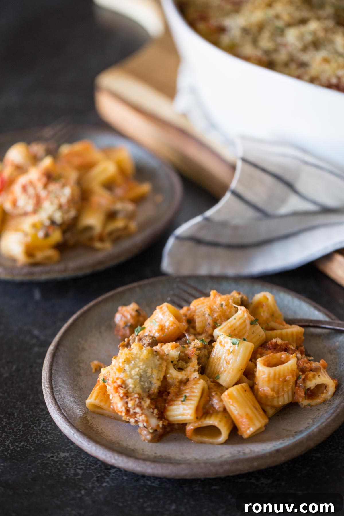 Creamy Tomato Alfredo Pasta Bake with Melted Mozzarella 4 Two plates of Cheesy Tomato Alfredo Pasta Bake sitting next to the baking dish.