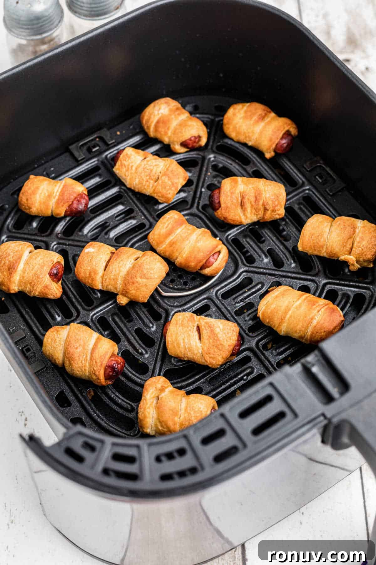 Crispy Air Fryer Pigs in a Blanket Recipe 2 An air fryer basket full of pigs in blankets.