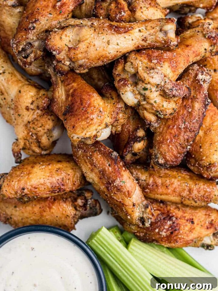 A close up shot of some air fried ranch chicken wings with some celery and ranch dip.