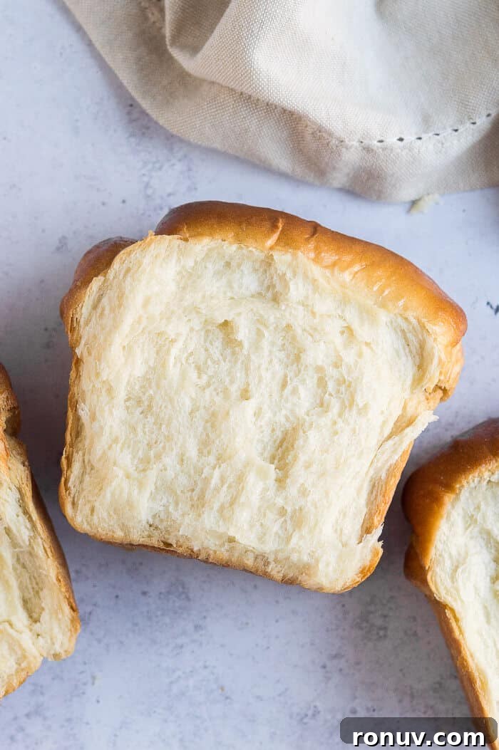 Sliced vegan Hokkaido milk bread slices of milk bread on a grey background with a beige cloth.