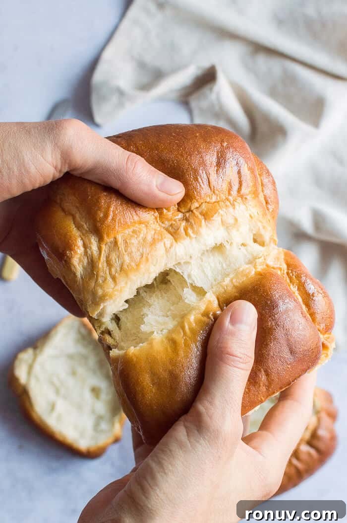 Vegan Hokkaido milk bread Hands tearing apart a loaf of vegan Hokkaido milk bread