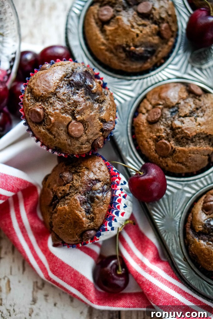 Homemade Cherry Chocolate Muffins Recipe 3 Two Cherry Chocolate muffins next to a pan of muffins and cherries.