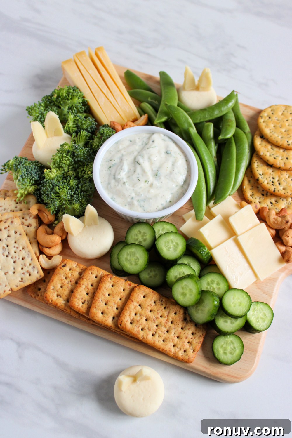 DIY Adorable Easter Charcuterie Board Ideas 4 Spring charcuterie board featuring bunny cheeses, crackers, and spring vegetables