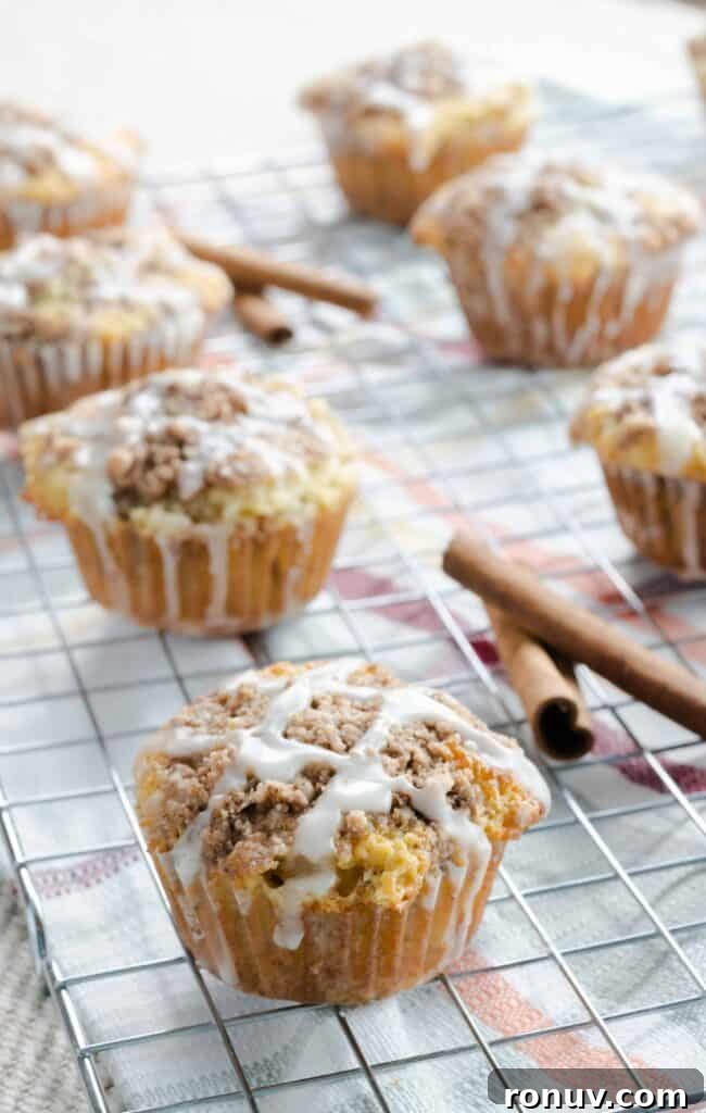 A deliciously moist coffee cake filled with a layer of brown sugar and cinnamon. Sour cream coffee cake muffins resting on wire rack and drizzled with glaze.